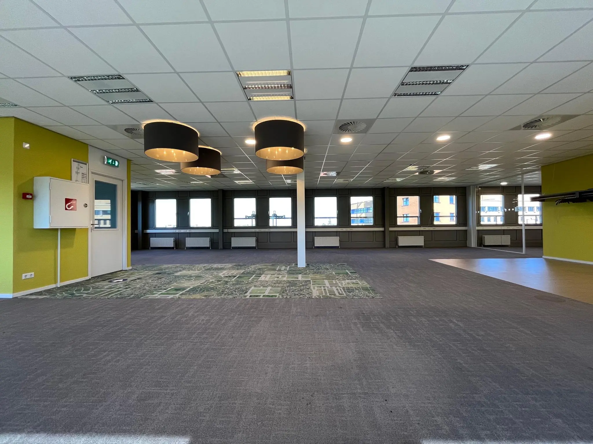 Ruime, lege kantoorruimte aan de Barchman Wuytierslaan met grote ramen, groene accenten en moderne verlichting.